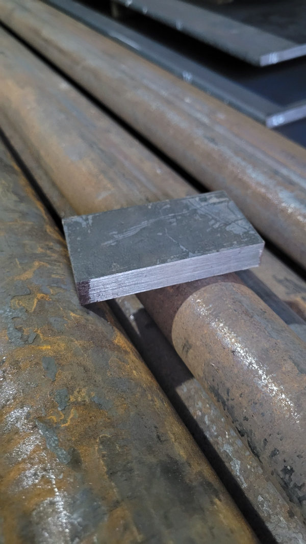 Tepi potongan plat baja SK3 di atas batang baja
