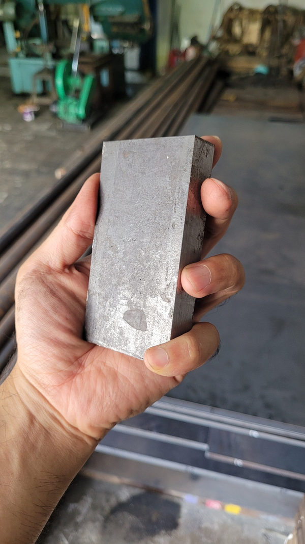 Sisi dan permukaan potongan plat baja VCN di tangan
