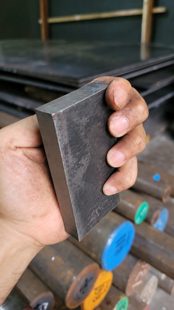 Potongan besi plat hitam dipegang dengan permukaan dan ketebalan terlihat