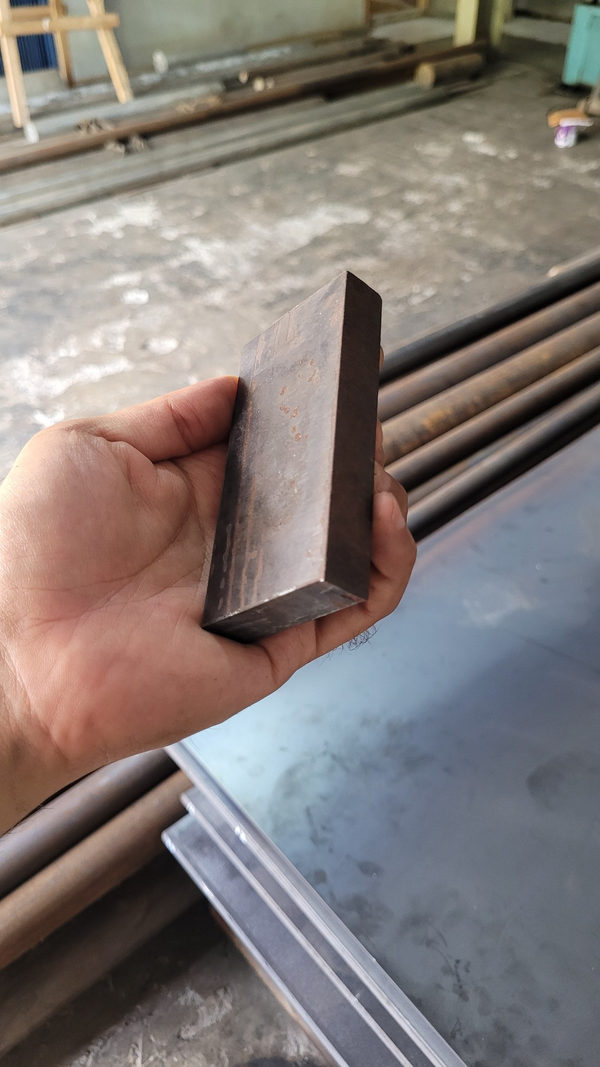 Contoh plat besi ST42 dipegang untuk menunjukkan ukuran potong