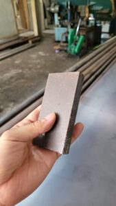 Potongan besi plat SS400 dipegang dengan tangan